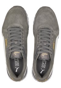 Šedé suede tenisky s šněrovacím designem, obsahující zlaté akcenty a bílý boční panel. Texturovaný povrch s polstrovanou stélkou označenou "SOFT."