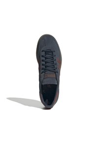 Sneaker in pelle scamosciata nera con strisce marroni, punta rotonda, lacci piatti e suola in gomma texturizzata, con un logo discreto sulla linguetta.