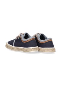 Zapatos de lona azul marino con un cuello de textil gris claro, detalles en cuero marrón y una suela de cuerda de yute. Cintas redondas y costuras reforzadas.
