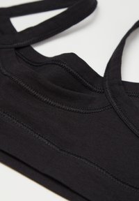 Černá sportovní podprsenka z elastického materiálu, s dvojitými ramínky, jemnými švy a hladkým povrchem.