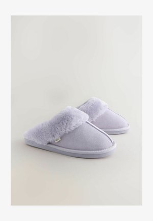 Chaussons lavande clair avec un bord en fausse fourrure douce et une texture semblable au daim. Ils disposent d'une semelle rembourrée et d'un détail de couture blanche.