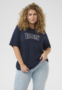 Marinblå bomullströja med korta ärmar och texten "BIEN" i vitt. Avslappnad passform, slät textur. Bärs med ljusblå denimjeans.