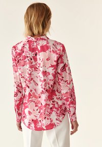 Blomstret skjorte med knapper i pink og hvid, med rundet kant, lange ærmer og et let stof med et iøjnefaldende printdesign.
