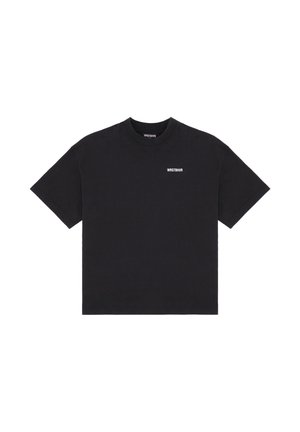 Musta lyhythihainen t-paita, jossa "WRSTBHVR" on painettu pienin valkoisin kirjaimin vasempaan rintaan ja kauluksen sisäpuolelle.