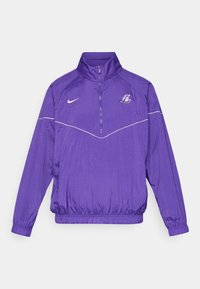 Nike lila széldzseki negyed cipzárral, rugalmas mandzsettákkal és derékpánttal, fehér részletekkel és logóval a mellkason.