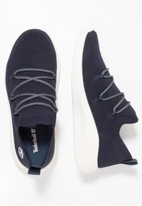 Baskets en maille bleu marine avec lacets élastiques, semelle en caoutchouc blanche et languette au talon. Tige en maille texturée pour une meilleure respirabilité.