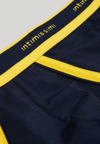Marineblaue Unterwäsche mit einem gelben Gummibund, der den Markennamen "Intimissimi" in gelbem Text zeigt. Weicher, glatter Stoff.