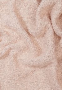 Tissu texturé rose clair avec une surface douce et duveteuse, montrant des plis drapés et des variations subtiles de teintes.