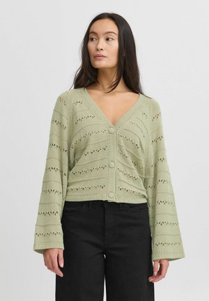 Cardigan tricoté vert clair avec un col en V, fermeture à boutons et manches évasées. Présente des rayures horizontales et des motifs ajourés sur l'ensemble.