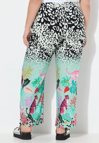 Wijd uitlopende broek met een zwart-wit dierenprint die overgaat in mintgroen, versierd met kleurrijke tropische patronen en afbeeldingen van tijgers.