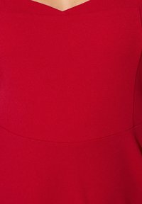 Czerwona sukienka z dopasowanym, gładkim gorsetem i dekoltem w kształcie litery V. Bez widocznych wzorów czy akcentów.