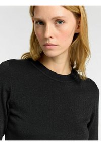 Musta ribbed-neuletakki, jossa on pyöreä pääntie ja kapea siluetti, jossa on hienovarainen kiilto kankaan rakenteessa.