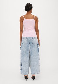Rosa tettsittende tanktop med tynne stropper og lyseblå vide cargo jeans med lommer og falmet vask.