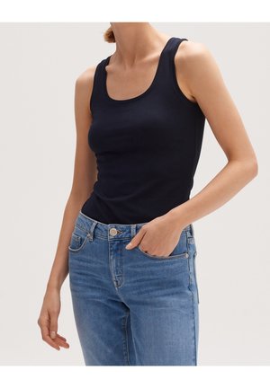 Marineblå tanktop i bomuld med rund halsudskæring og brede stropper, parret med lyseblå denimjeans med forlommer.