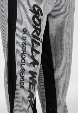 Grijze en zwarte sportbroeken met een geribbelde textuur, voorzien van het "GORILLA WEAR OLD SCHOOL SERIES" logo in vet zwart op de zijkant.