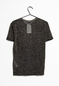 T-shirt nera a maniche corte con un motivo a pois dorati, scollatura rotonda e etichetta in stoffa sul retro. Appesa a un gancio nero.