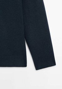 Pull bleu marine foncé avec une texture douce, des poignets côtelés et des lignes épurées. Mise au point sur les détails des manches et de l'ourlet sans motifs ni ornements.