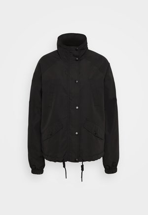 Schwarze Jacke mit hohem Kragen, Druckknöpfen, zwei Vordertaschen, elastischen Bündchen und Kordelzügen am Saum. Aus einem glatten, langlebigen Stoff gefertigt.
