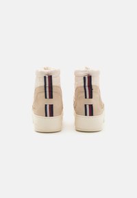 Beige højtop sneakers med ruskind, quilted stof, kontrasterende røde og marineblå stribede accenter, samt en struktureret gummisål.