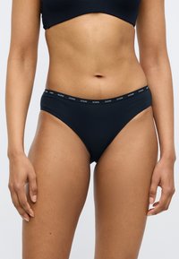 Sort bomulds-hipstertrusse med en tynd logo i linningen. Stoffet er glat med et tætsiddende design og få sømme for komfort.