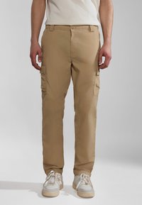 Beige cargo bukser lavet af letvægtsstof, med sidelommer, lige pasform og knaplukning. Båret med hvide sneakers.