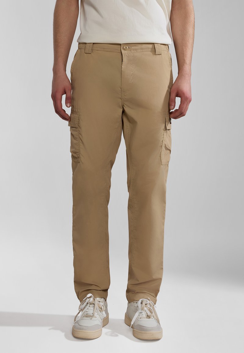 Beige cargo bukser lavet af letvægtsstof, med sidelommer, lige pasform og knaplukning. Båret med hvide sneakers.