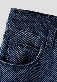 Tejido de mezclilla azul oscuro con un diseño texturizado de tejido diagonal, con un pequeño bolsillo frontal y un detalle de costura más denso cerca de la cinturilla.