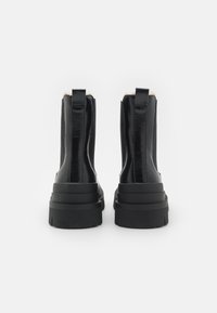 Μαύρα μποτάκια αστραγάλου με λείο δέρμα, ελαστικές πλαϊνές πάνες και χοντρή, υφασμάτινη σόλα με στοιβαγμένο σχέδιο.