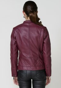 Veste de moto en cuir bourgogne avec des détails matelassés, des poignets zippés et une coupe ajustée. La vue de dos montre une texture lisse et des coutures.
