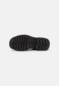 Black rubber sole with deep zigzag treads for traction. Rounded toe and slightly raised heel for stability. Smooth, matte finish.