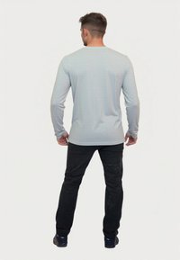 Világosszürke, hosszú ujjas póló, strukturált anyagból, fekete nadrággal párosítva. A póló kerek nyakkal és slim fit szabással rendelkezik.