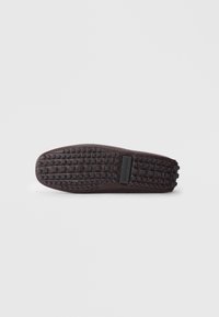 Suela de zapato de goma marrón oscuro con una superficie texturizada que presenta pequeños patrones cuadrados y rectangulares, etiquetada como "CALL IT SPRING."