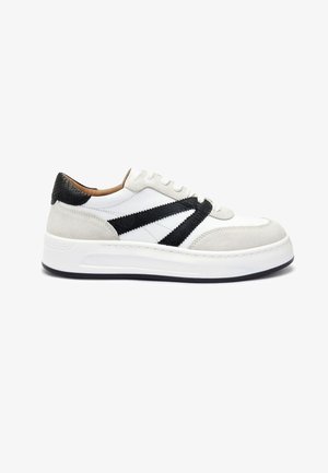 Baskets en nubuck blanc avec un détail de bande texturée noire, semelle plate blanche, bout rond et accent de talon noir contrastant.