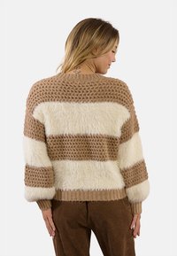 Maglione a righe soffice in beige e crema con un design a maglia testurizzata. Presenta un collo rotondo e polsini a coste, evidenziando una vestibilità rilassata.