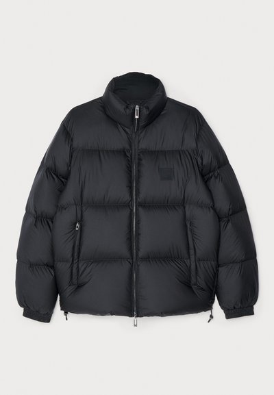 Sort pufferjakke med høj krave, lynlåslukning og elastiske manchetter. Har kviltet design og to sidelommer. Holdbart, isoleret materiale.