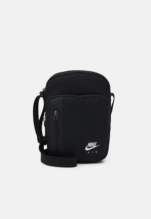 Czarna torba Nike Air crossbody z regulowanym paskiem, przednią kieszenią na zamek i białym logo w dolnym prawym rogu.