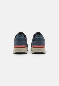 Marineblaue Sneakers mit gepolstertem Fersenbereich, beigem Sohlenrand und korallenfarbenen Akzenten. Verfügt über "Blauer"-Branding auf der Rückseite und strukturierte Stoffdetails.