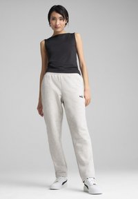 Svart ärmlös topp, ljusgrå sweatpants med elastisk midja, logotyp, kombinerat med vita platåskor och en enkel frisyr.