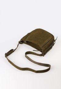 Olivegrünes Wildleder-Crossbody-Bag mit rechteckiger Form, verstellbarem Tragegurt und Reißverschluss. Bemerkenswerte Details sind die Nähte und die strukturierte Oberfläche.