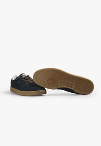 Zapatillas de ante azul oscuro con suela de goma beige. Presentan puntera redonda, cordones planos y una marca en el lateral. Suela texturizada con un patrón geométrico.