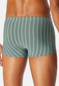 Men's boxer briefs in light teal with vertical black stripes. They feature a snug fit, seamless waistband, and smooth fabric texture.