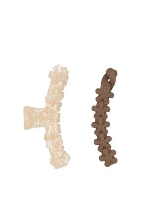 Due accessori per capelli: una molletta traslucida beige con motivo floreale e un elastico per capelli in silicone marrone a forma di fiori, testurizzato e flessibile.