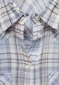 Button-up shirt made of lightweight fabric in a blue, white, and red plaid pattern. Features a collar, two buttons, and a pocket.