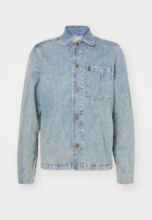 Chaqueta de denim azul claro con un cuello clásico, botones frontales y un bolsillo en el pecho. Presenta un corte relajado y detalles de costura visibles.