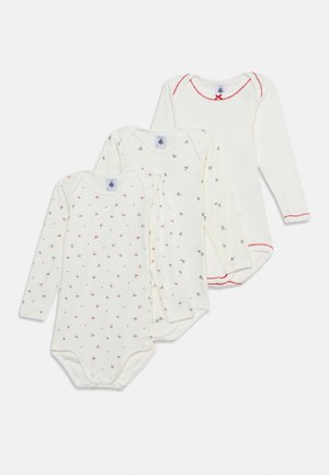 Trois bodies blancs à manches longues pour bébé, deux avec de petits imprimés floraux et un avec un galon rouge festonné au niveau du col, des manches et de l'ourlet.