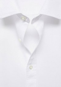 Camisa de cuello blanco con una tela texturizada, que presenta una tapeta de botones con botones transparentes y bordes de cuello suaves.