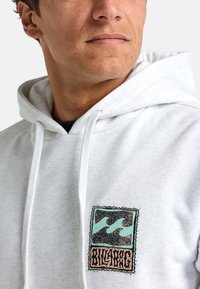 White cotton hoodie featuring a front pocket, drawstring hood, and a colorful graphic design with wavy patterns and logo.