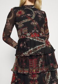 Mustapuku, jossa on pitkät hihat ja poimuttava muotoilu, koristeltuna monimutkaisilla kukka- ja arkkitehtonisilla kuvioilla punaisen ja vihreän sävyissä.