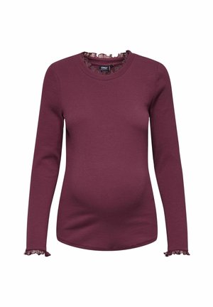 Maternity top in burgundy with long sleeves, ribbed texture, round neckline, and ruffled accents at the cuffs and collar.