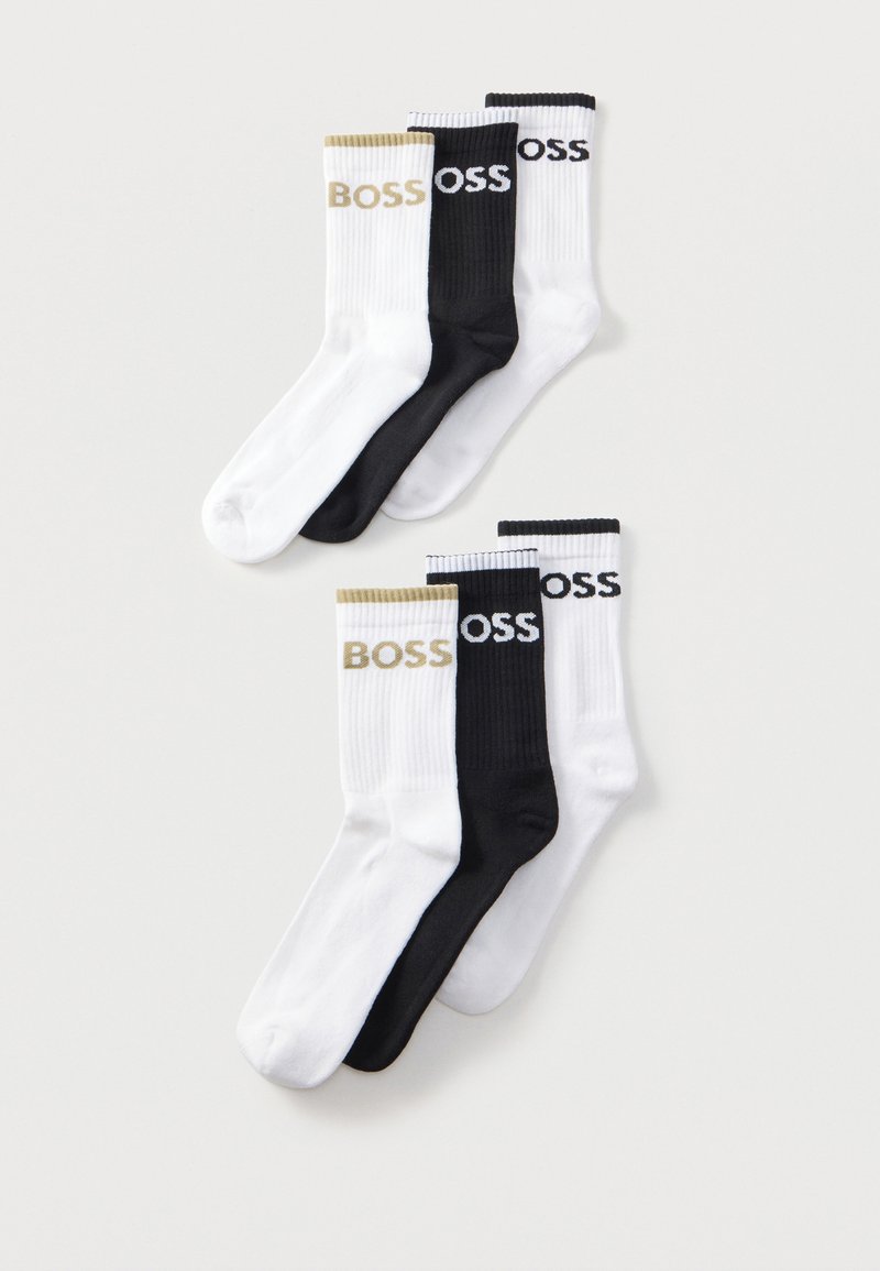 Six paires de chaussettes côtelées blanches et noires, chacune avec le logo "BOSS" près du haut en couleurs contrastées.